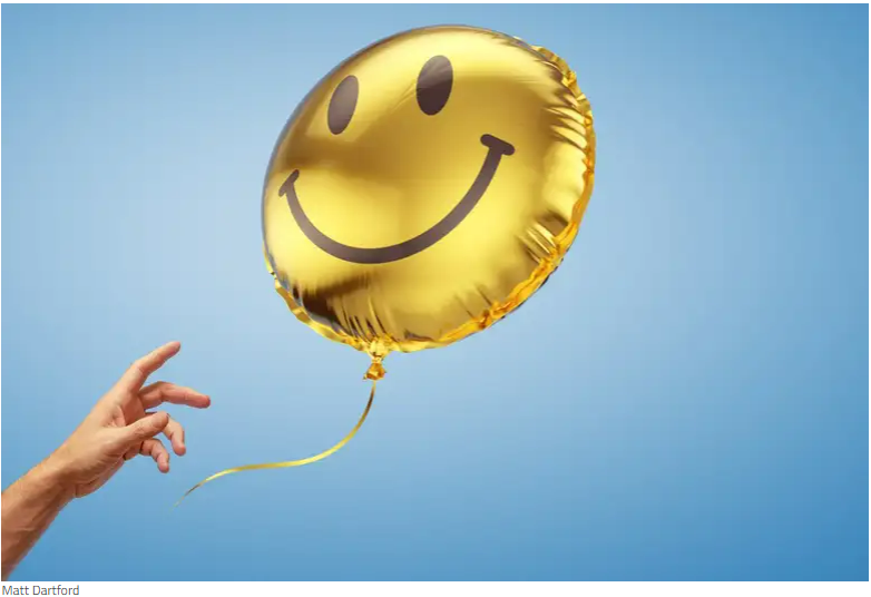 Hand reaching out to smiley face balloon