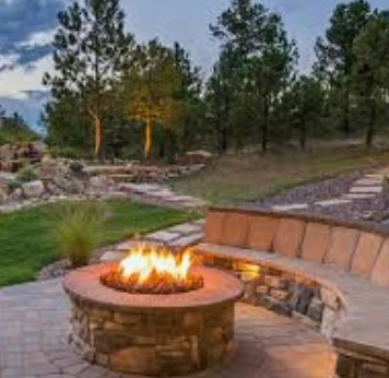 Lit stone fire pit on patio in forested yard