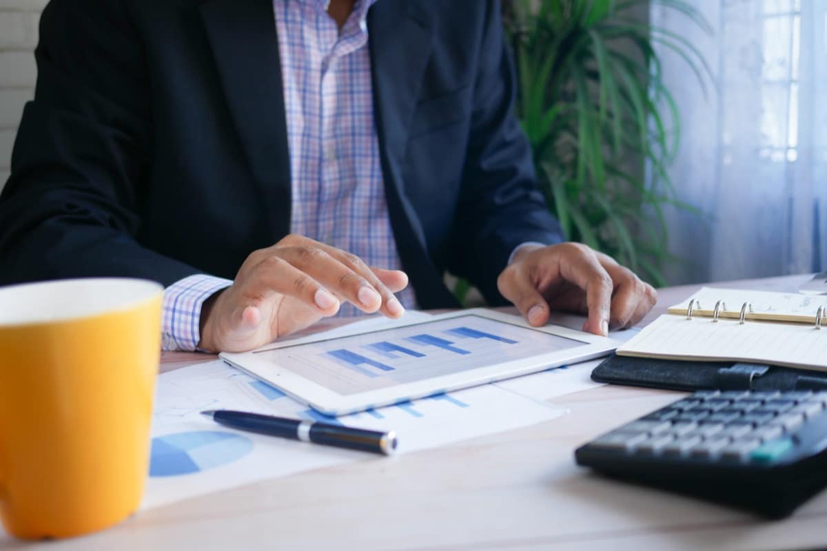 Man working at desk on tablet with calculator; rewards packages concept