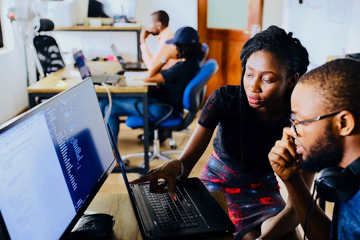 People sitting at computers, one giving instruction; upskilling and reskilling concept