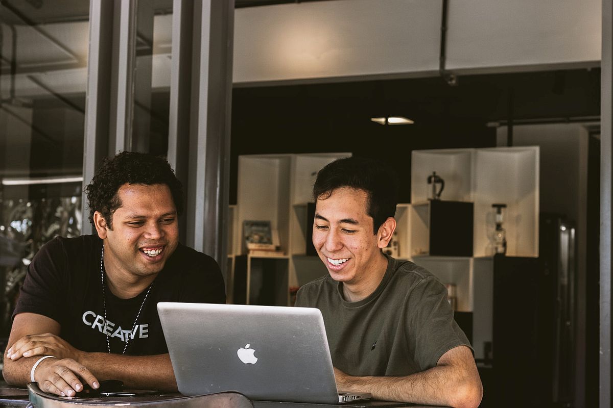 Two smiling men looking at laptop; retain more employees concept