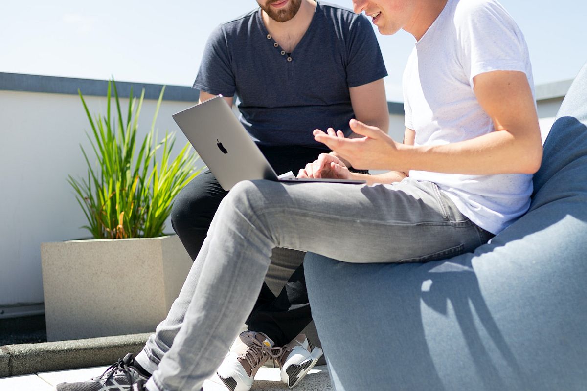 Two people having a discussion, with laptop open; rewards management platform concept