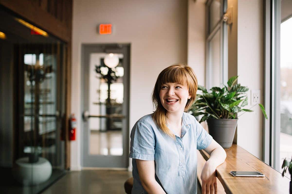 Smiling woman sitting at table; tailor rewards concept