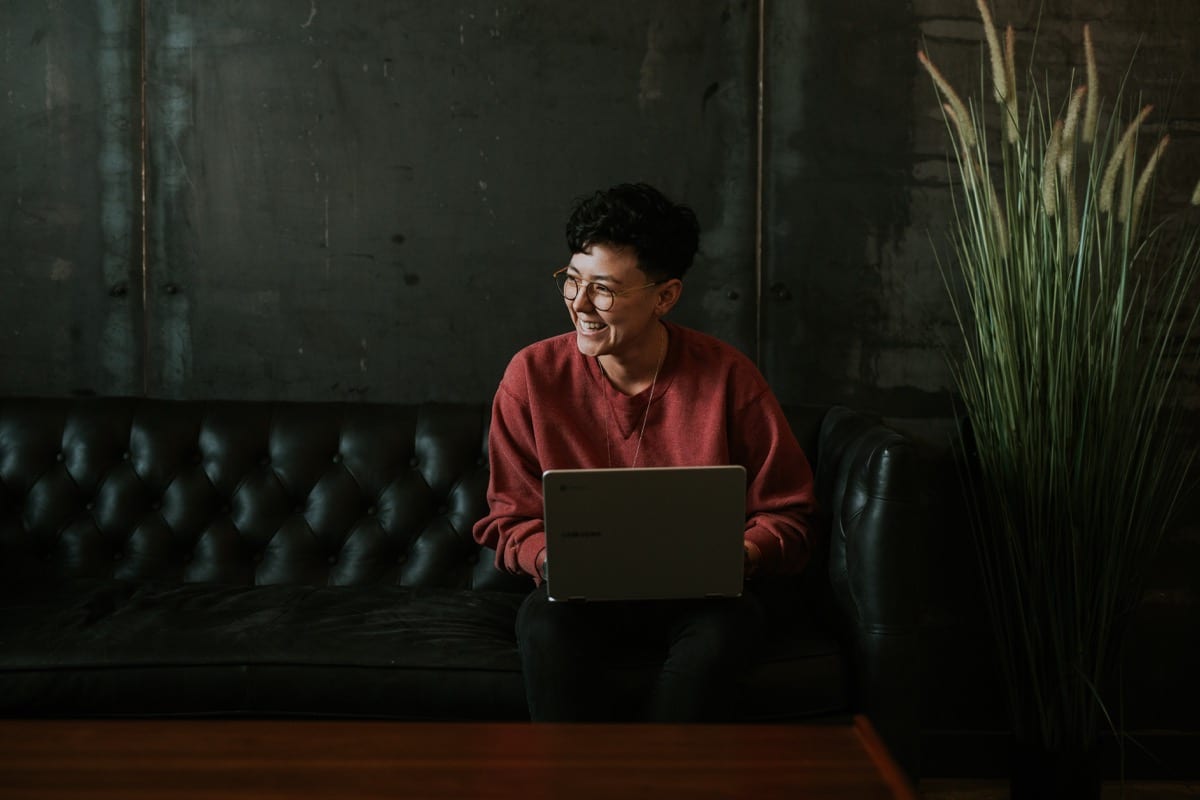 Smiling person at laptop; self-care benefits concept