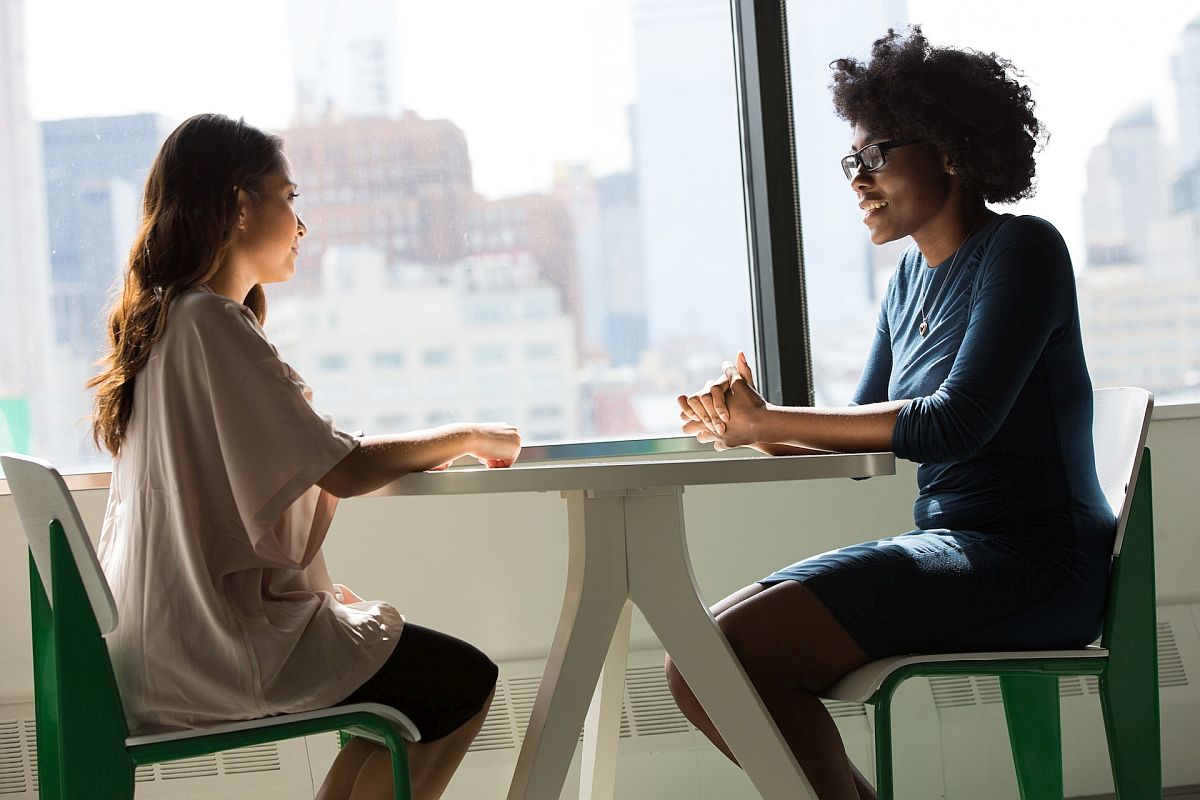 Two professional women talking; employee rewards dei concept