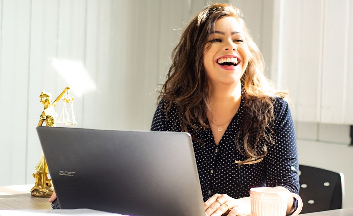Smiling woman sitting at desk with laptop; pay transparency concept