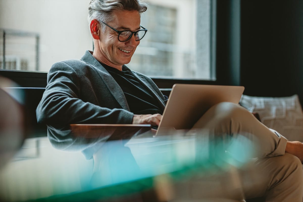 Smiling businessman sitting in office and working on laptop; factor inflation concept