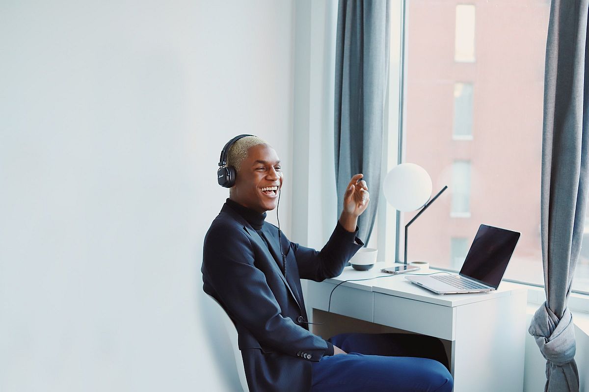 Laughing man wearing headphones, sitting in front of laptop; effective rewards concept