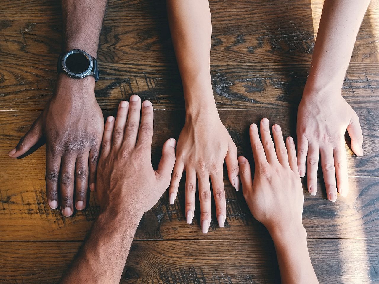 Close-up of people's hands on table; employee rewards dei concept