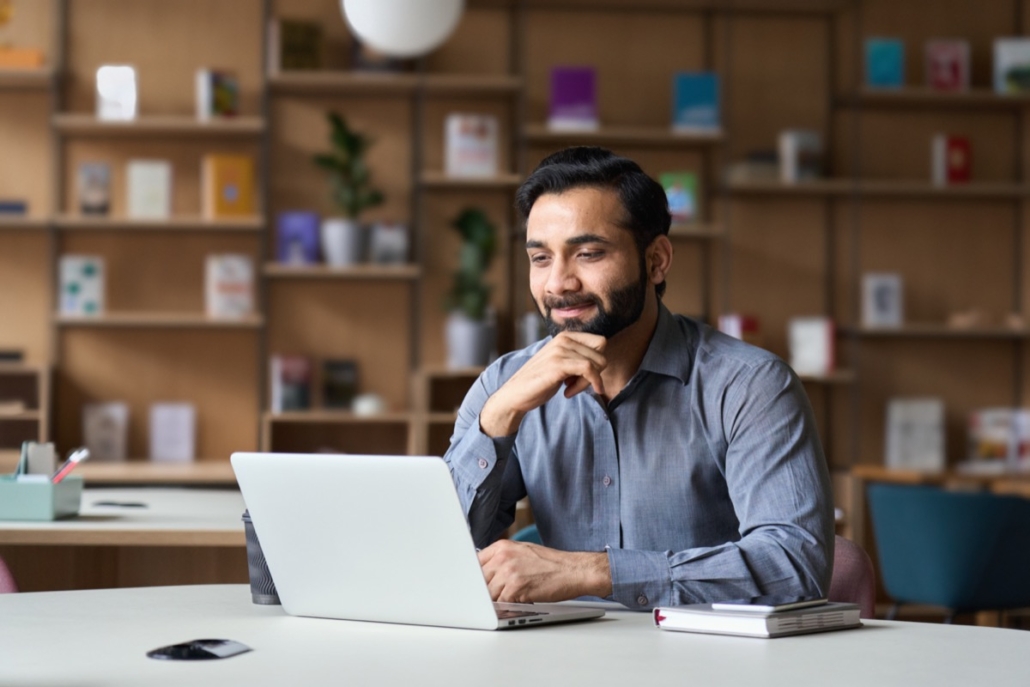 smiling man using laptop; benefits programs concept