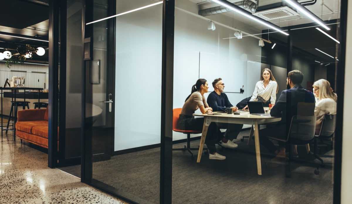 Team of diverse businesspeople having a meeting in a transparent boardroom; factor inflation concept