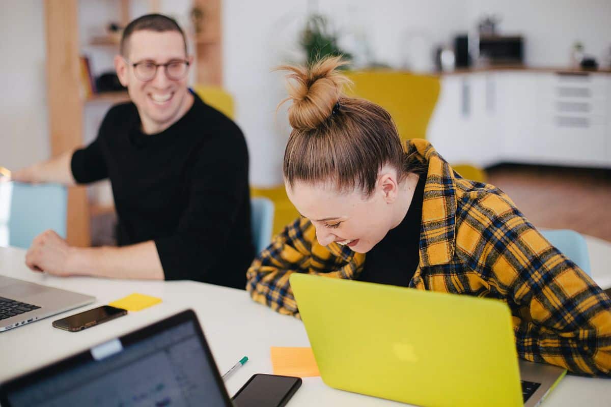 Two work colleagues laughing in the office; talent war concept