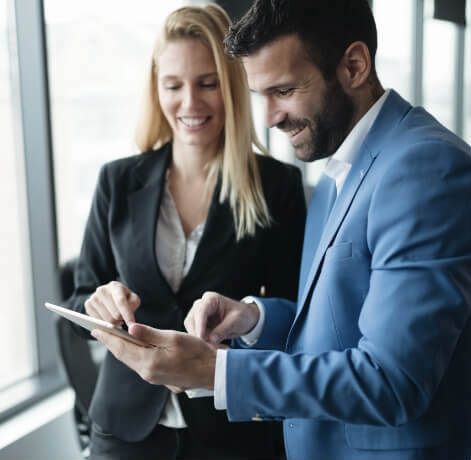 Woman and man smiling while looking at tablet